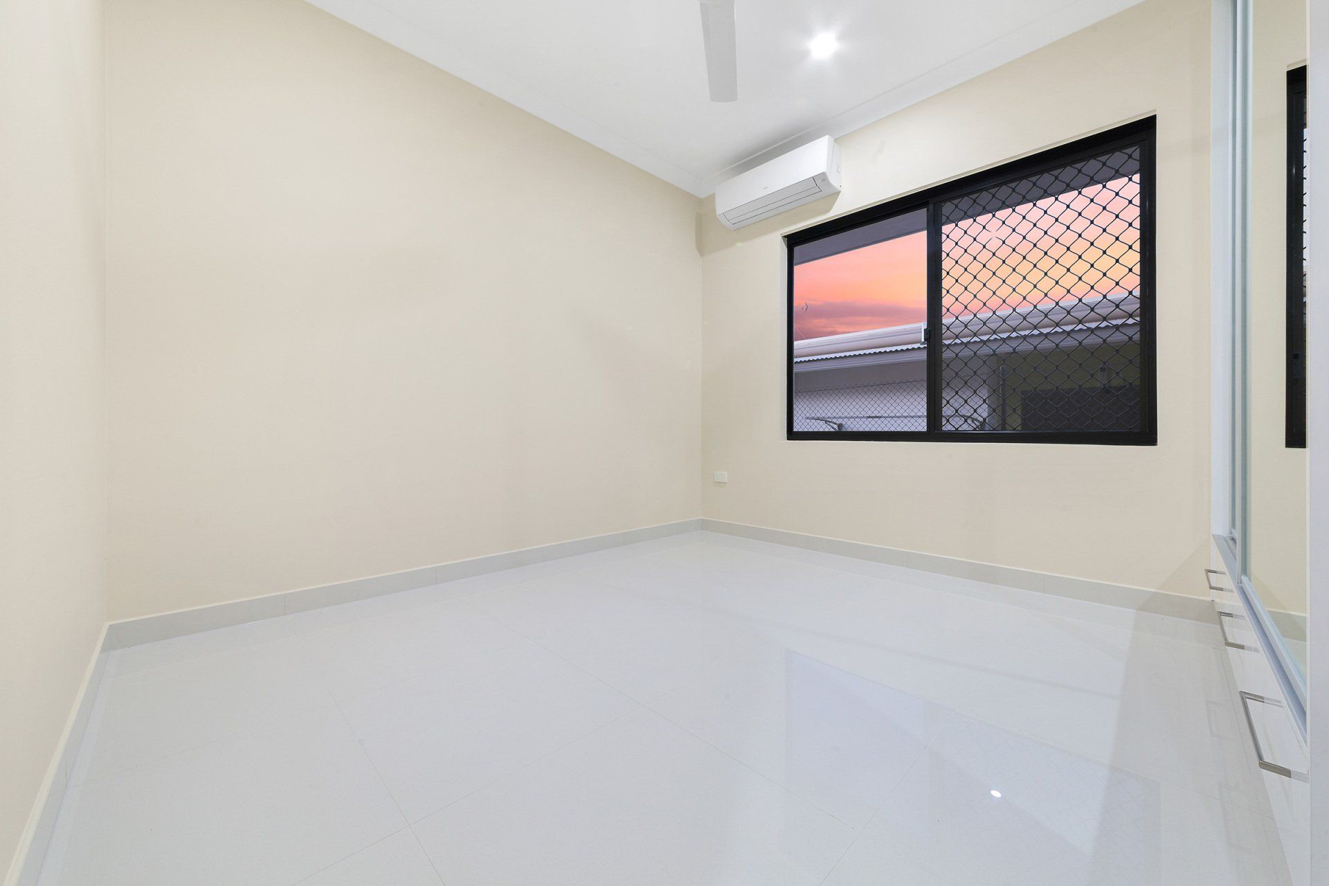 An empty room with a window and a ceiling fan.