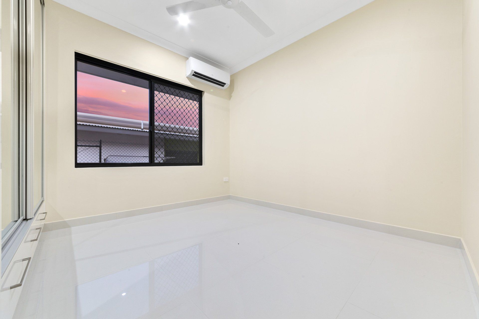 An empty room with a ceiling fan and a window.