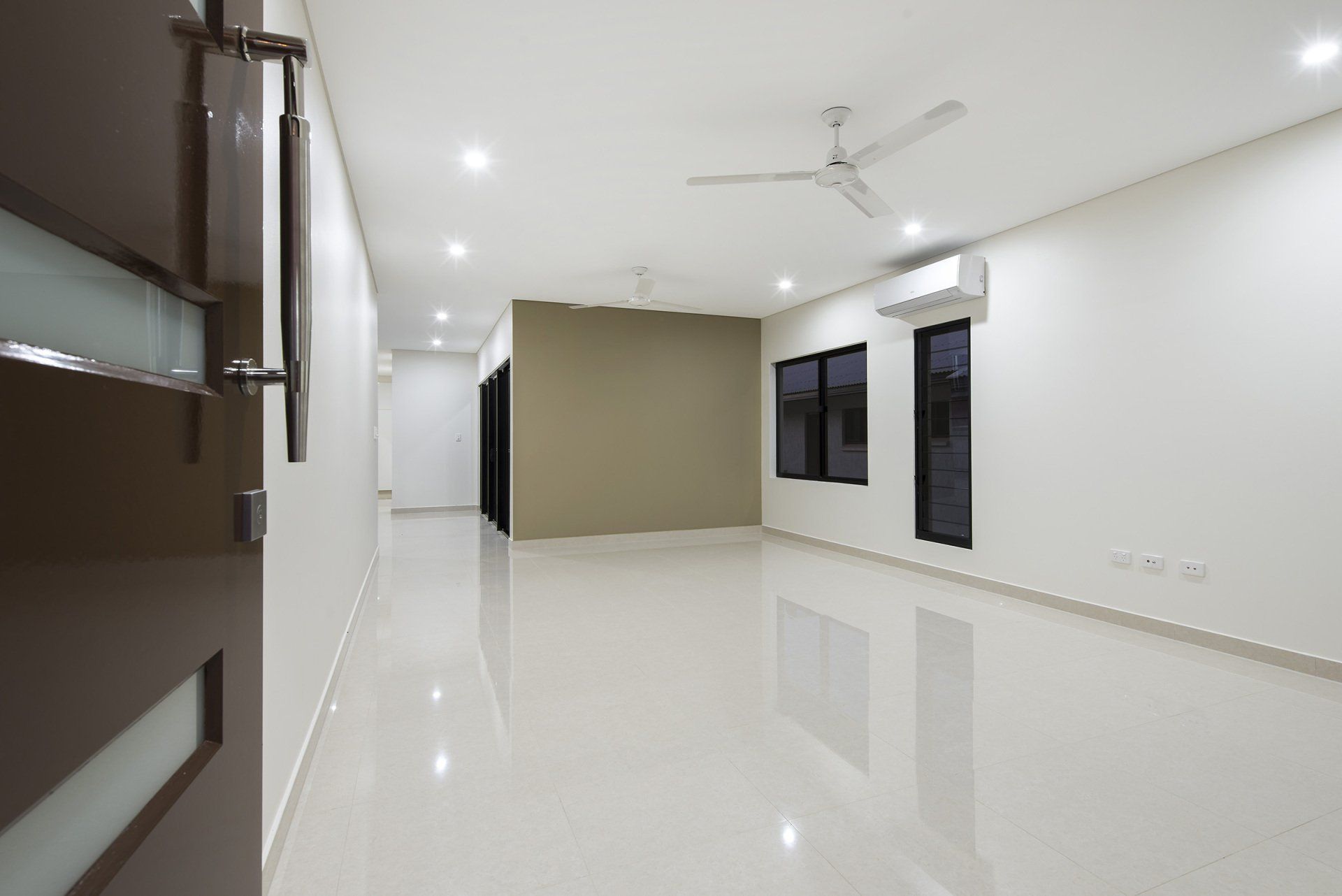 An empty room with white walls and a ceiling fan