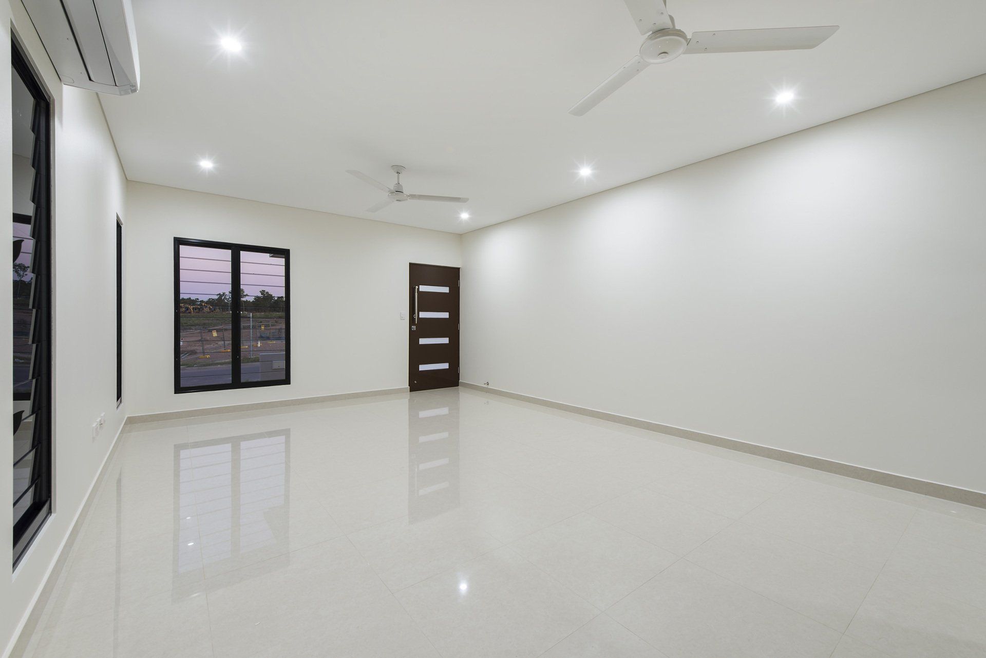 An empty room with white walls and a ceiling fan