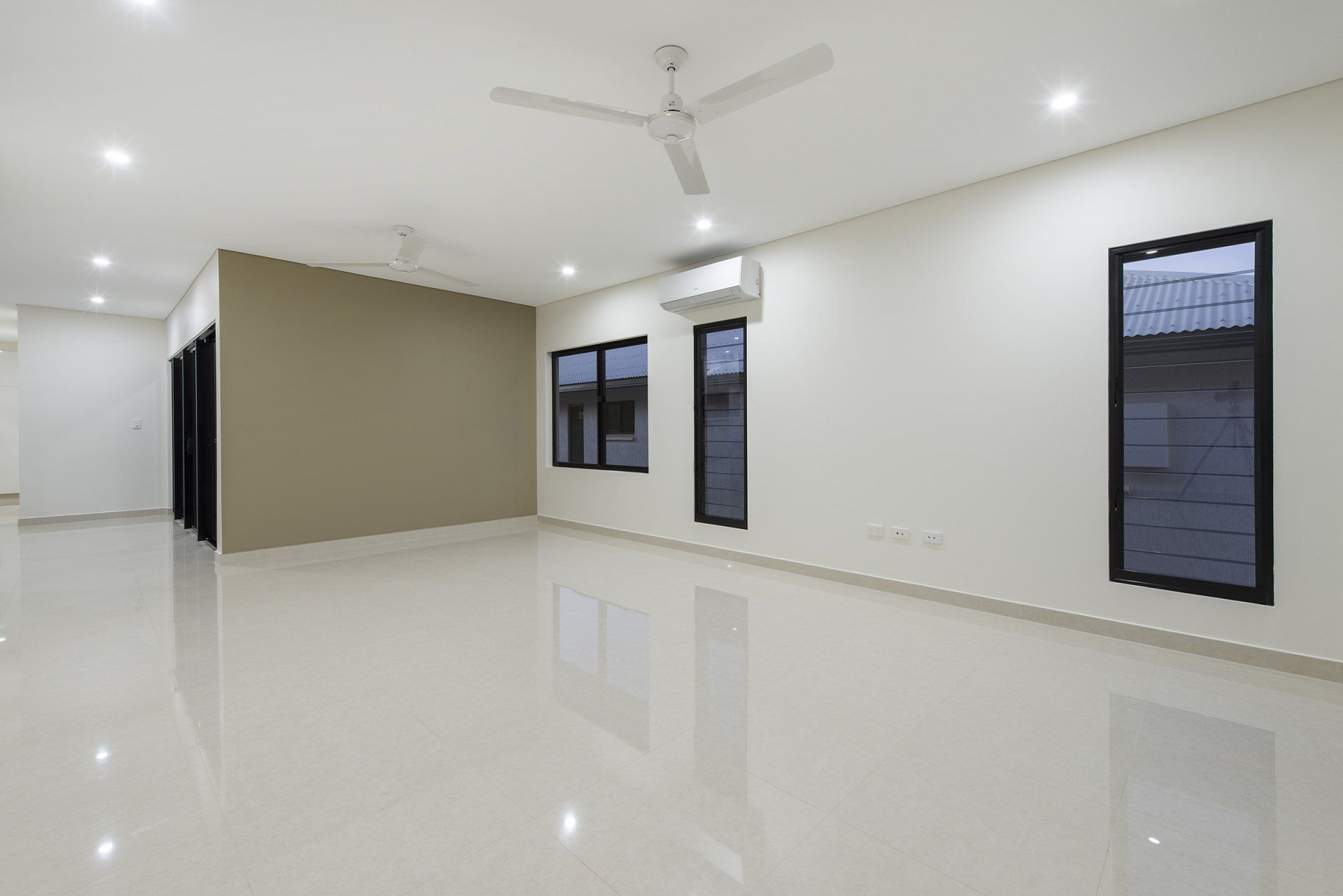A large empty room with a ceiling fan and windows.