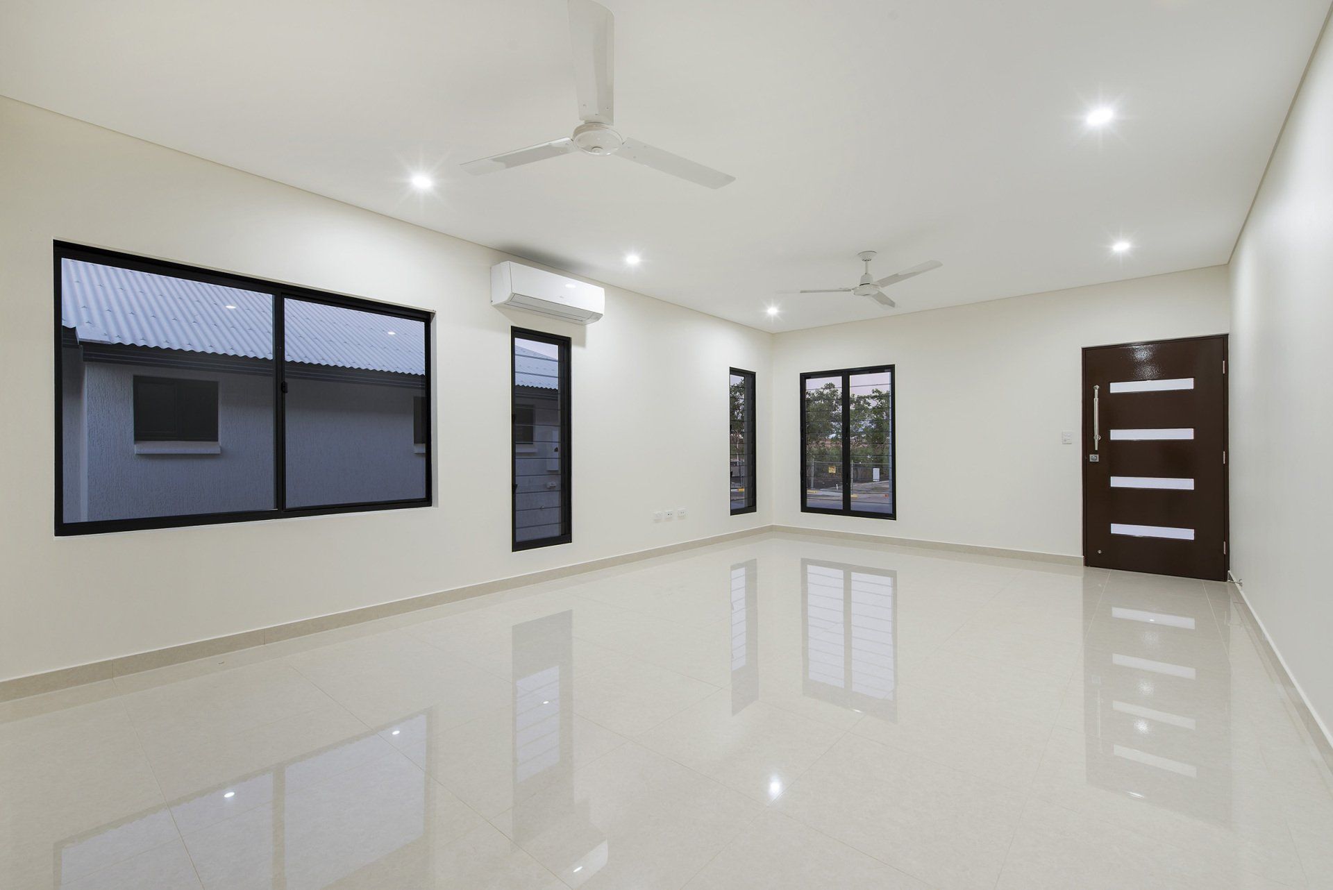 A large empty room with a ceiling fan and windows