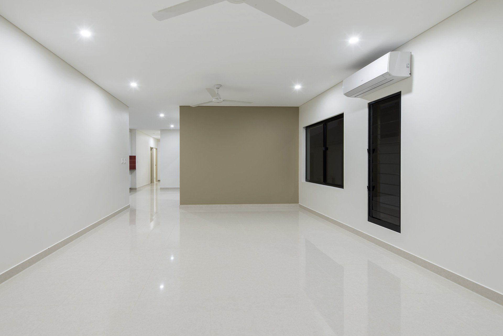 An empty room with white walls and a ceiling fan