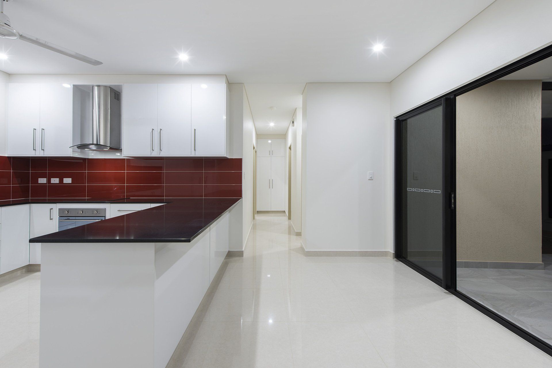 An empty kitchen with white cabinets and black counter tops