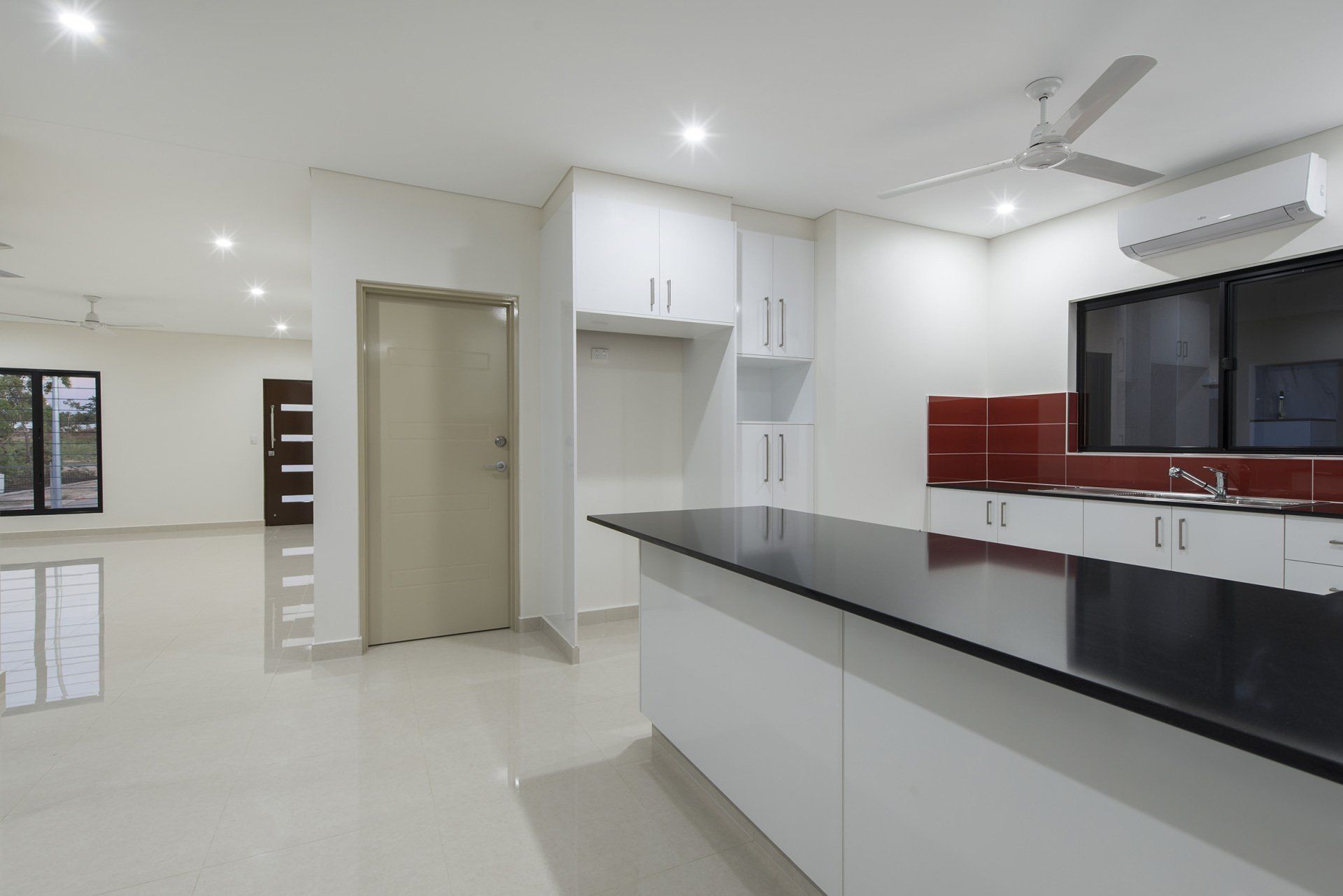 An empty kitchen with black counter tops and white cabinets