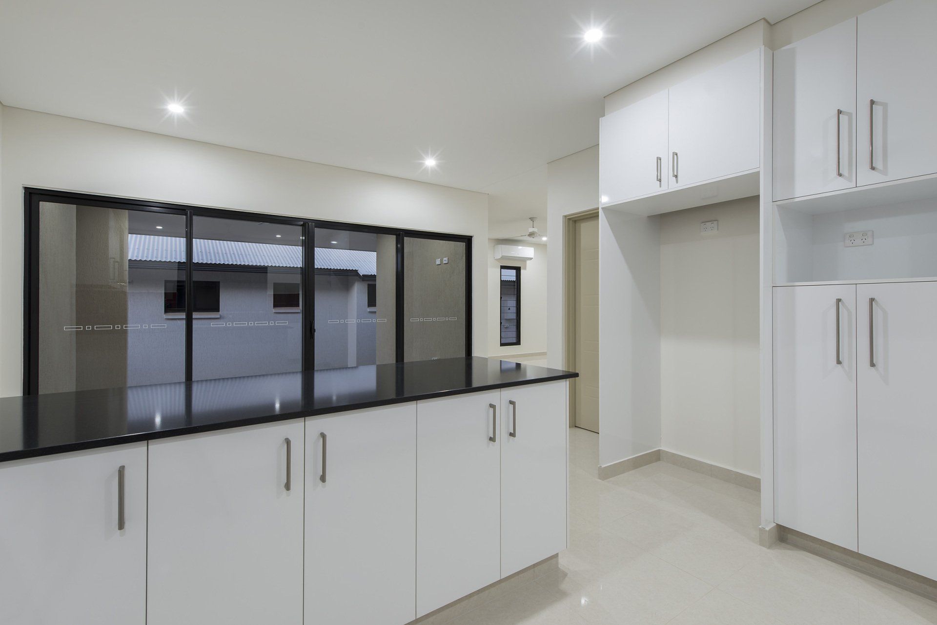 An empty kitchen with white cabinets and black counter tops.