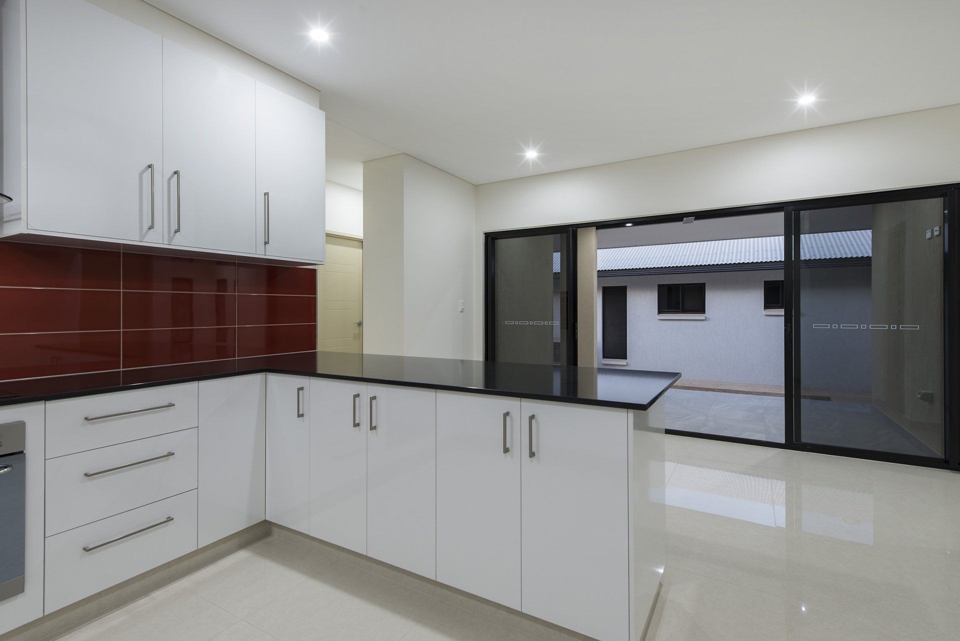 An empty kitchen with white cabinets and black counter tops