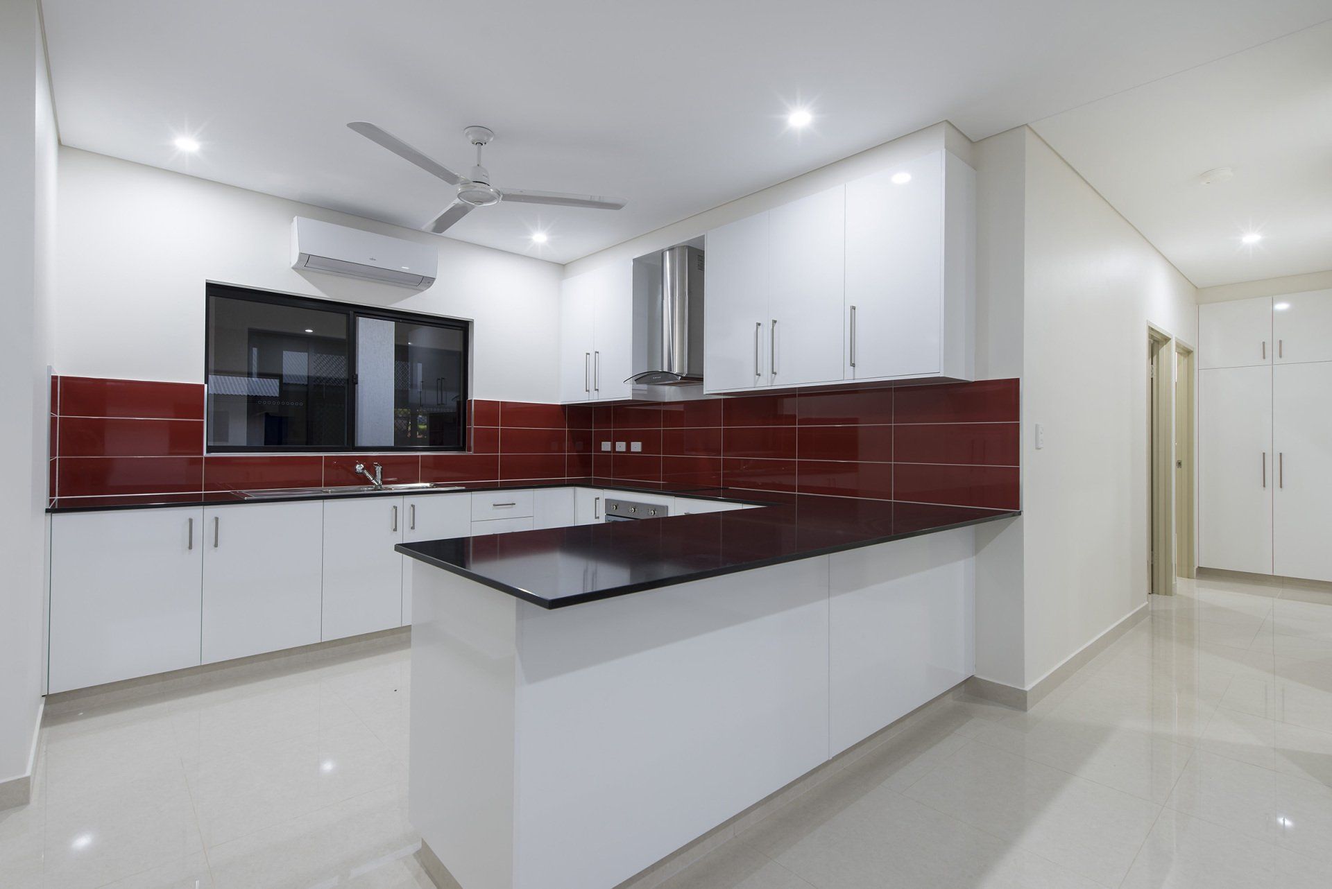 An empty kitchen with white cabinets and a black counter top.