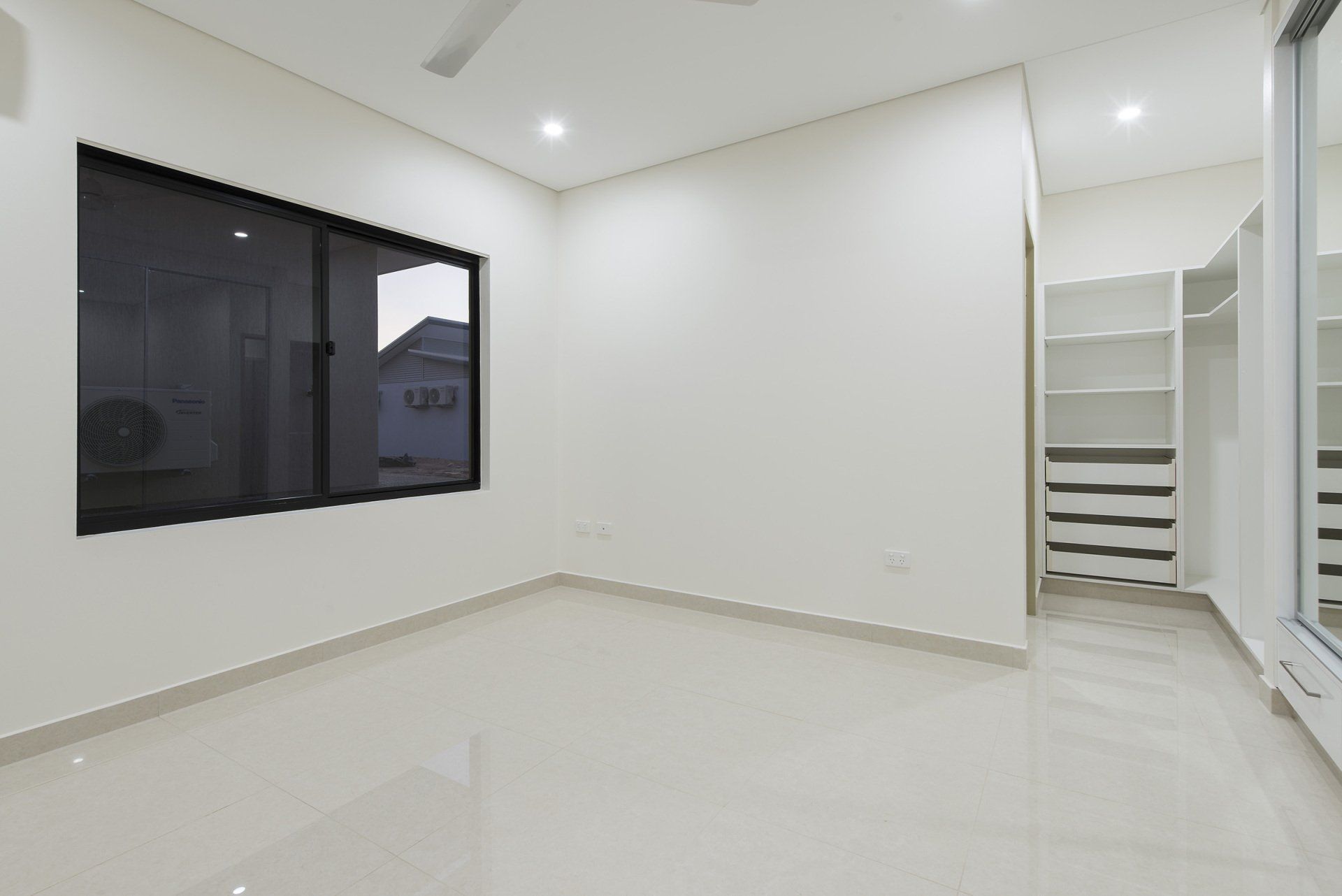 An empty bedroom with white walls and a walk in closet.