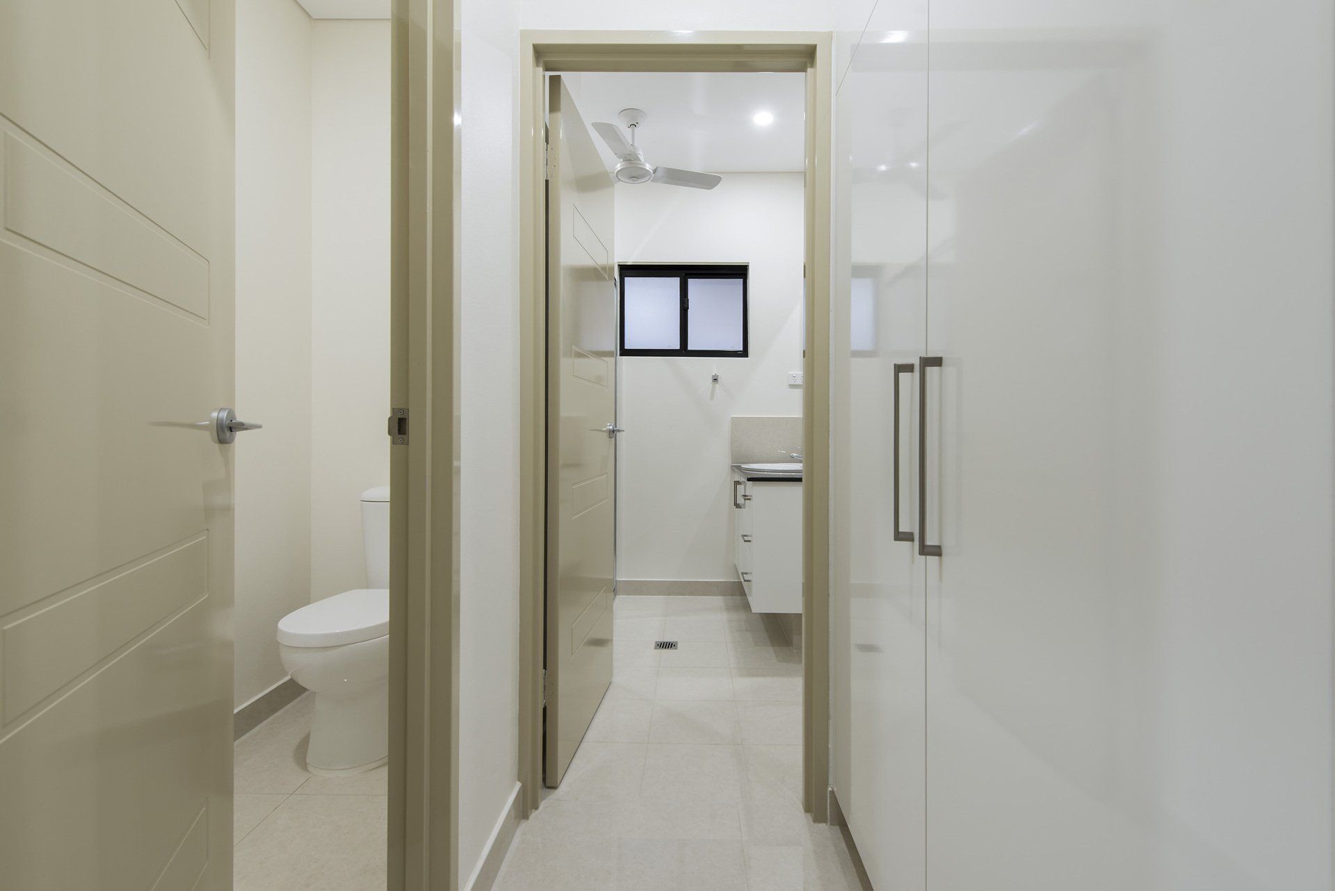 A hallway leading to a bathroom with a toilet and sink.