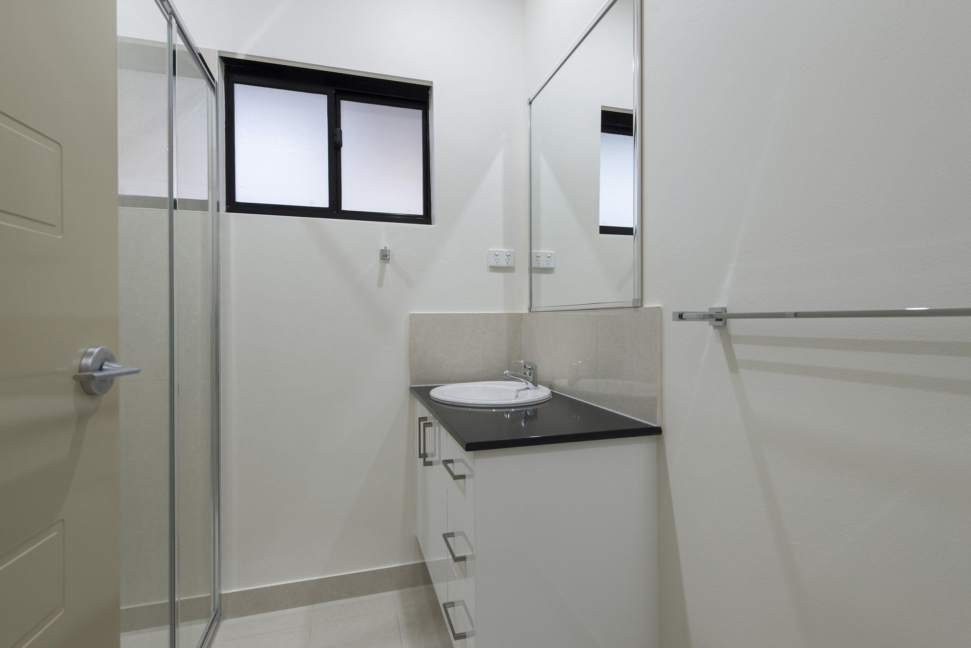 A bathroom with a sink , mirror and shower.