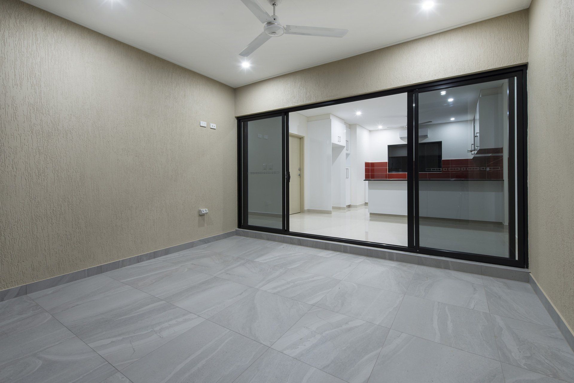 An empty room with sliding glass doors and a ceiling fan