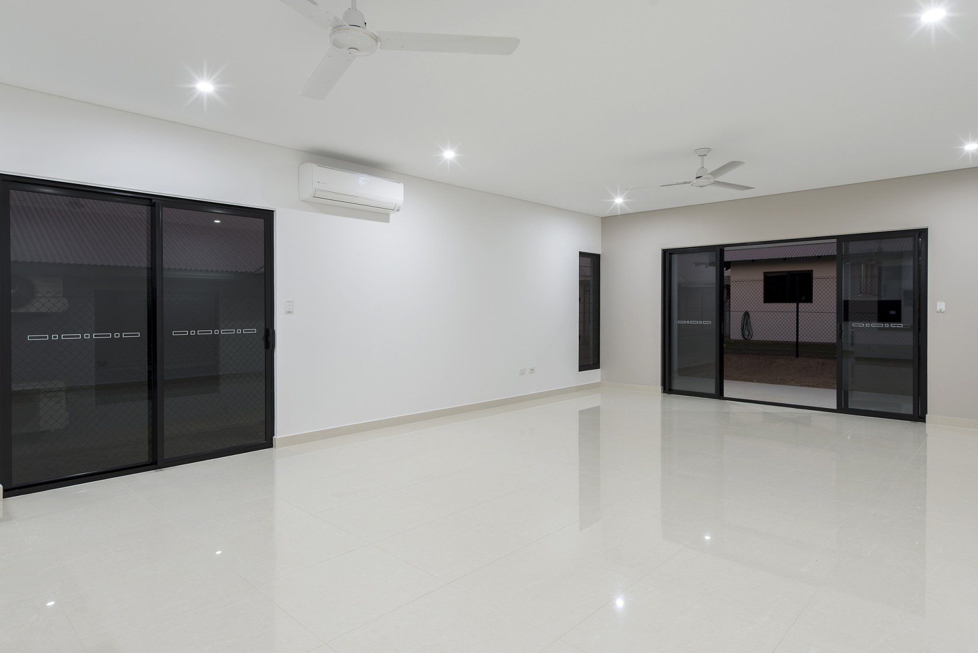 A large empty room with sliding glass doors and a ceiling fan.