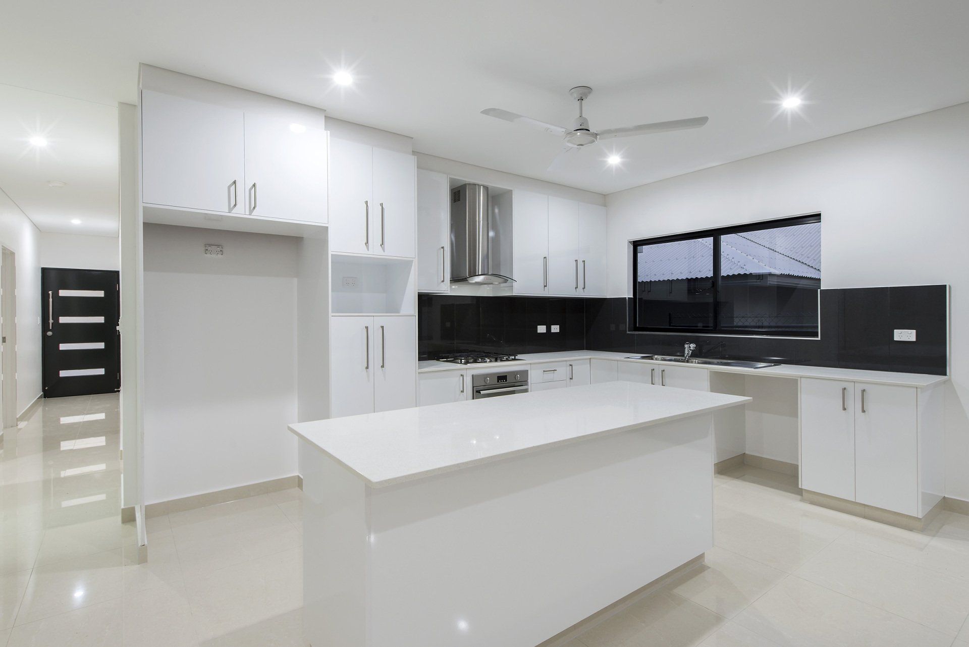 An empty kitchen with white cabinets and a large island.