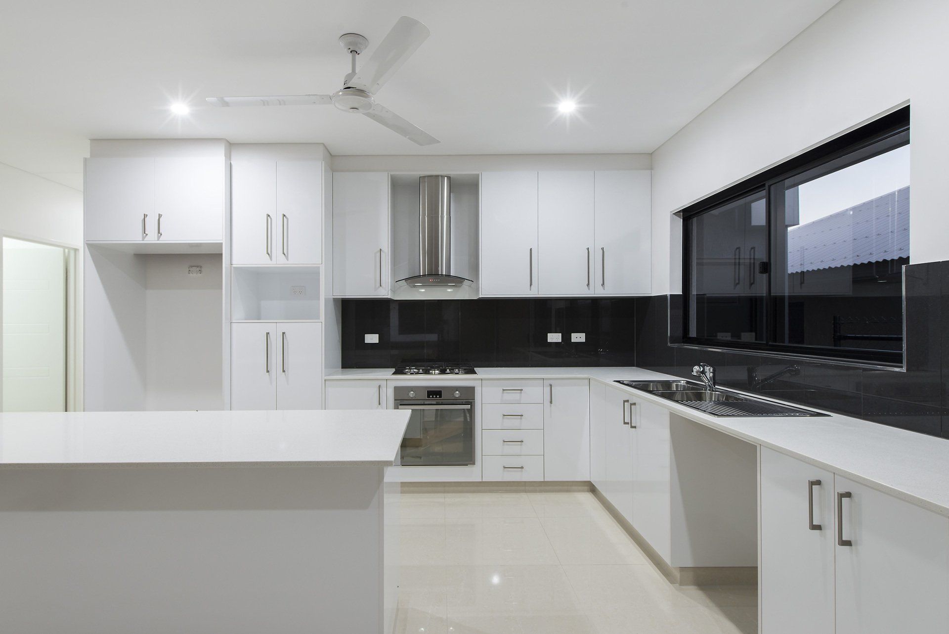 A kitchen with white cabinets and a ceiling fan