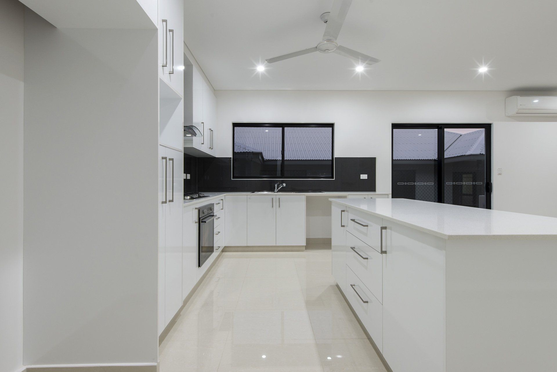 An empty kitchen with white cabinets and a large island.