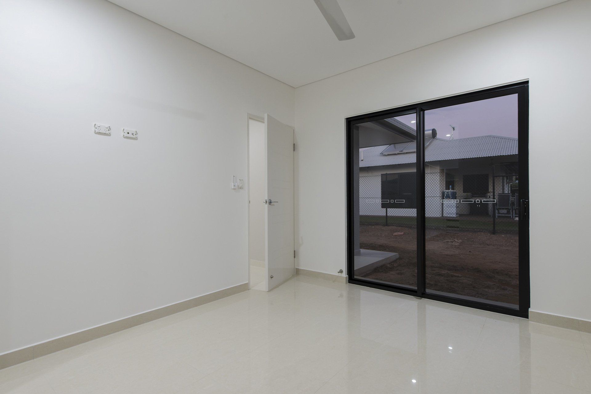 An empty room with a sliding glass door and a ceiling fan.