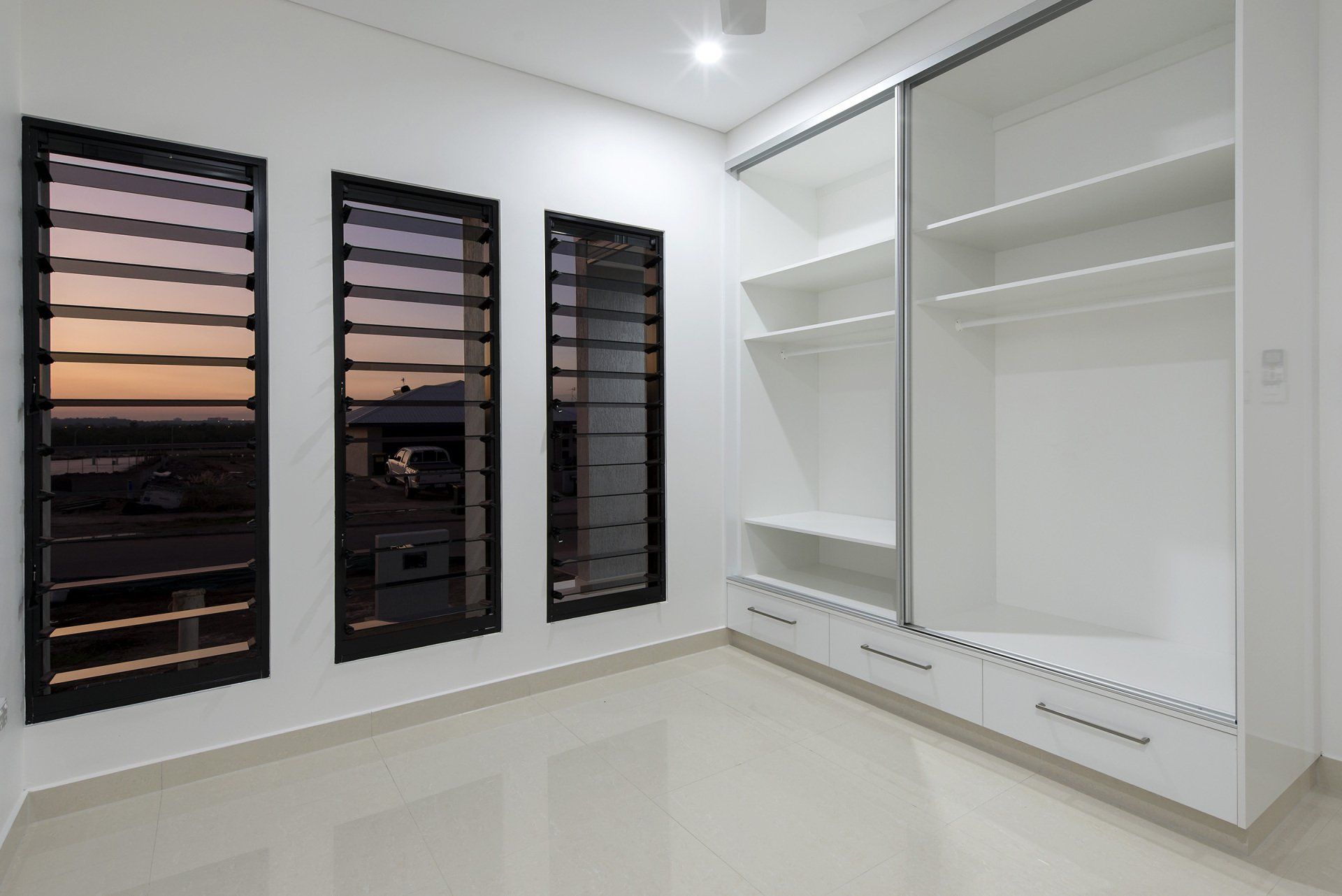 An empty room with a lot of shelves and windows.