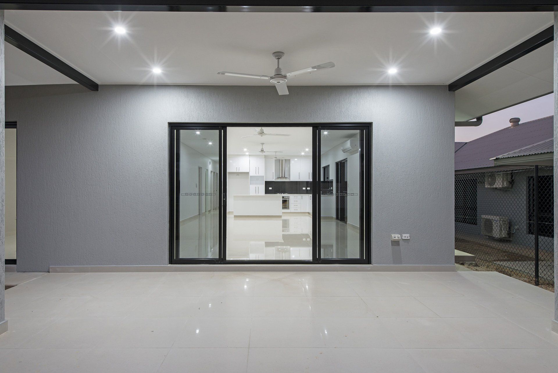 The backyard of a house with sliding glass doors and a ceiling fan.