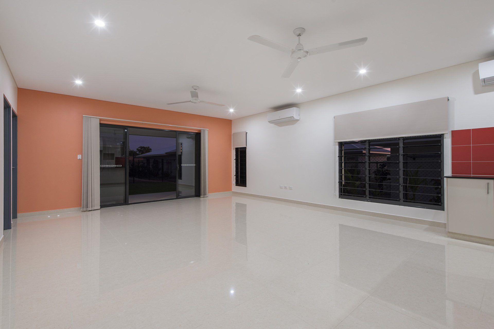 An empty living room with a ceiling fan and sliding glass doors.