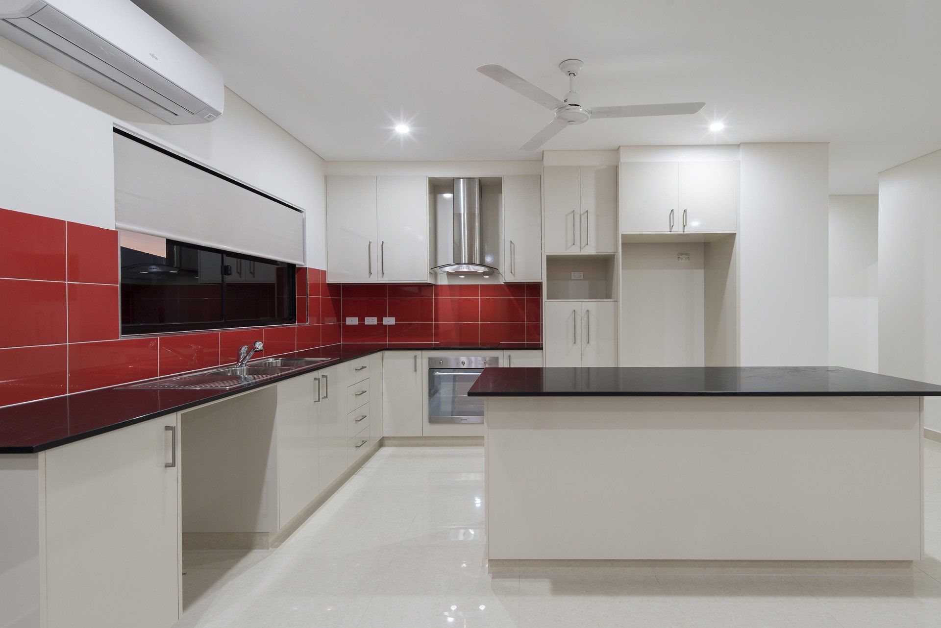 An empty kitchen with red tiles and black counter tops
