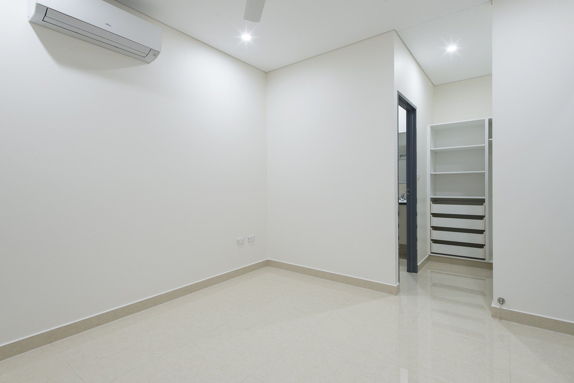 An empty bedroom with white walls and a closet.