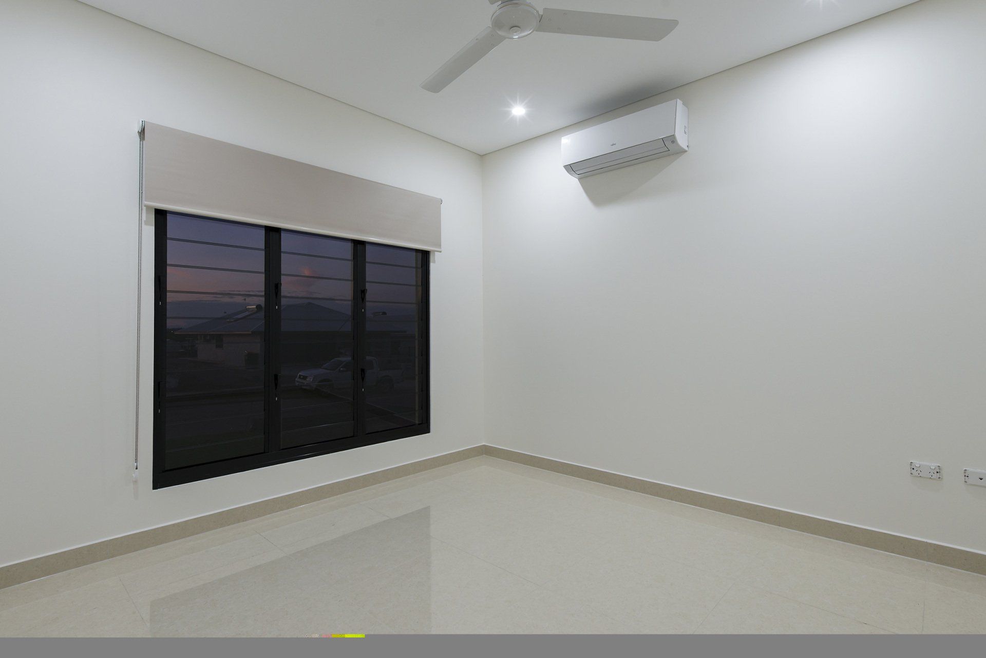 An empty room with a ceiling fan and a window.