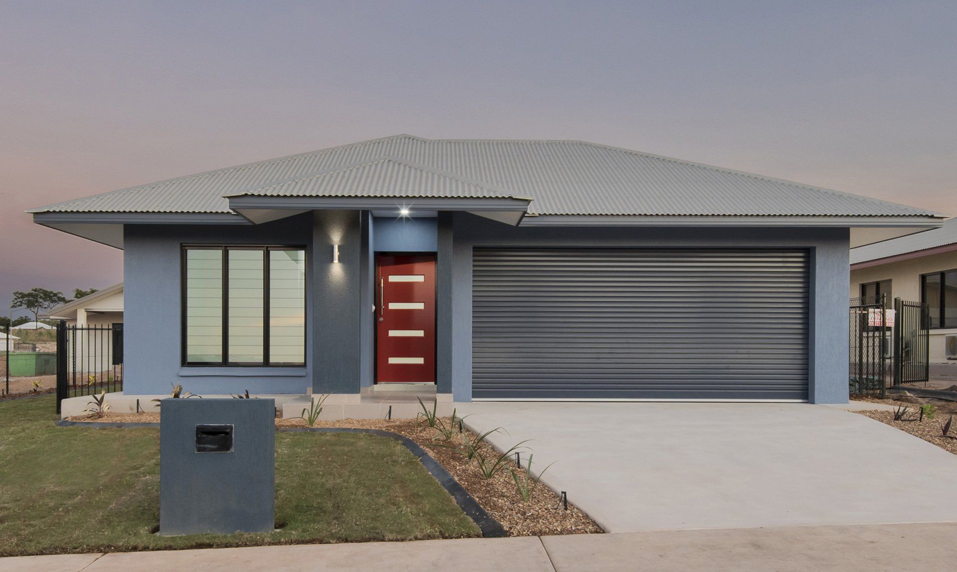 A blue house with a gray garage door and a red door