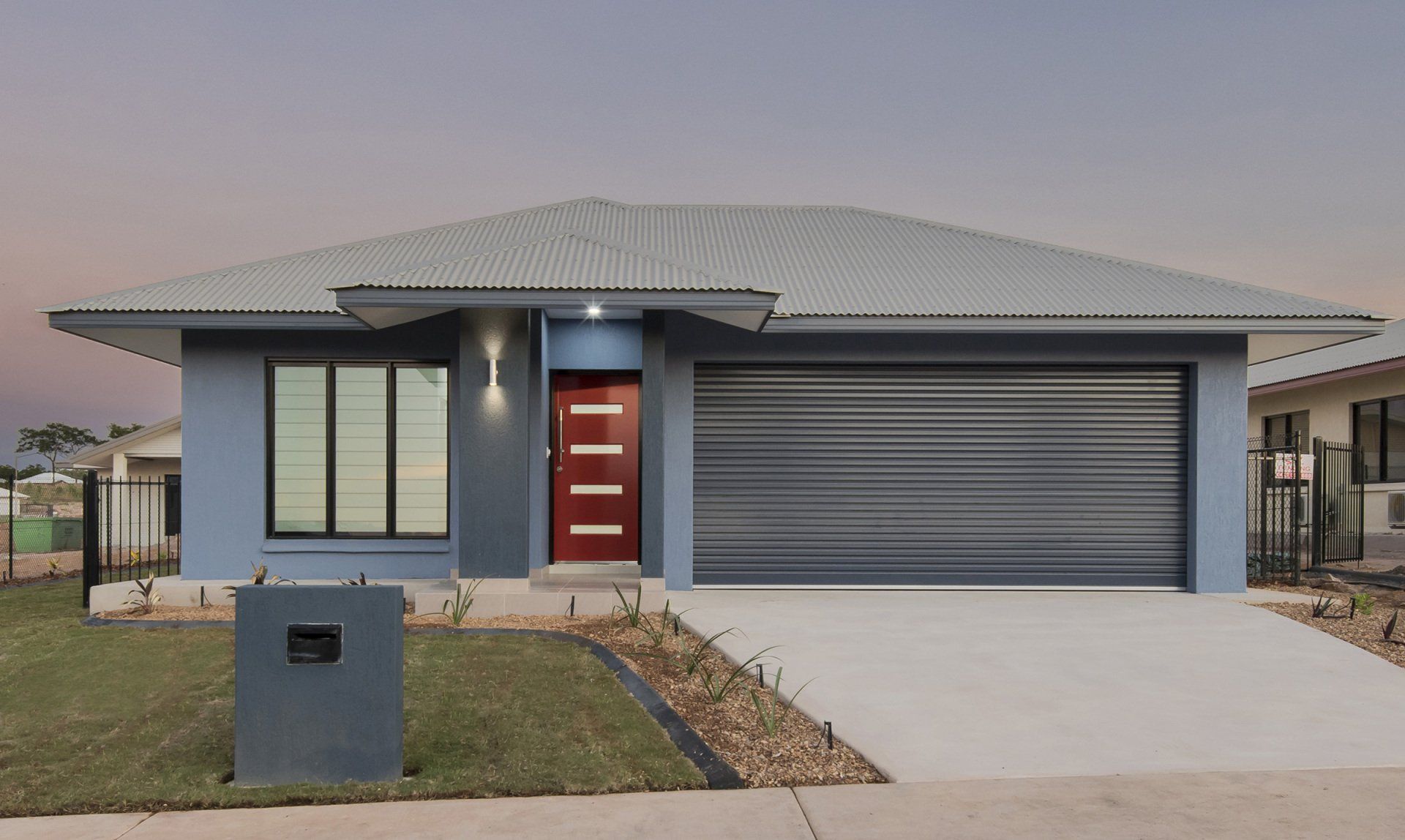 A blue house with a gray garage door and a red door