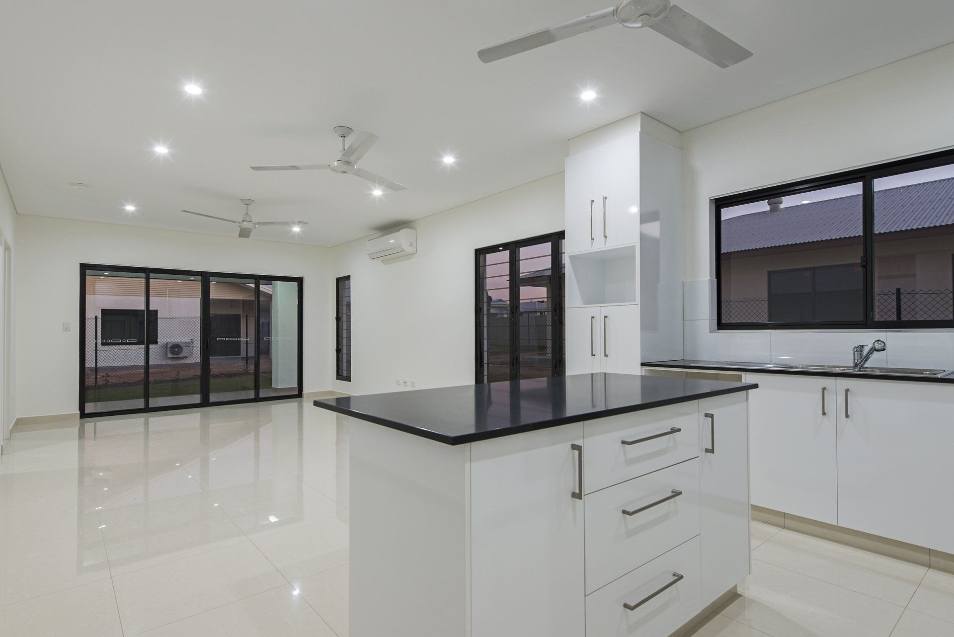 An empty kitchen with white cabinets and a black counter top.