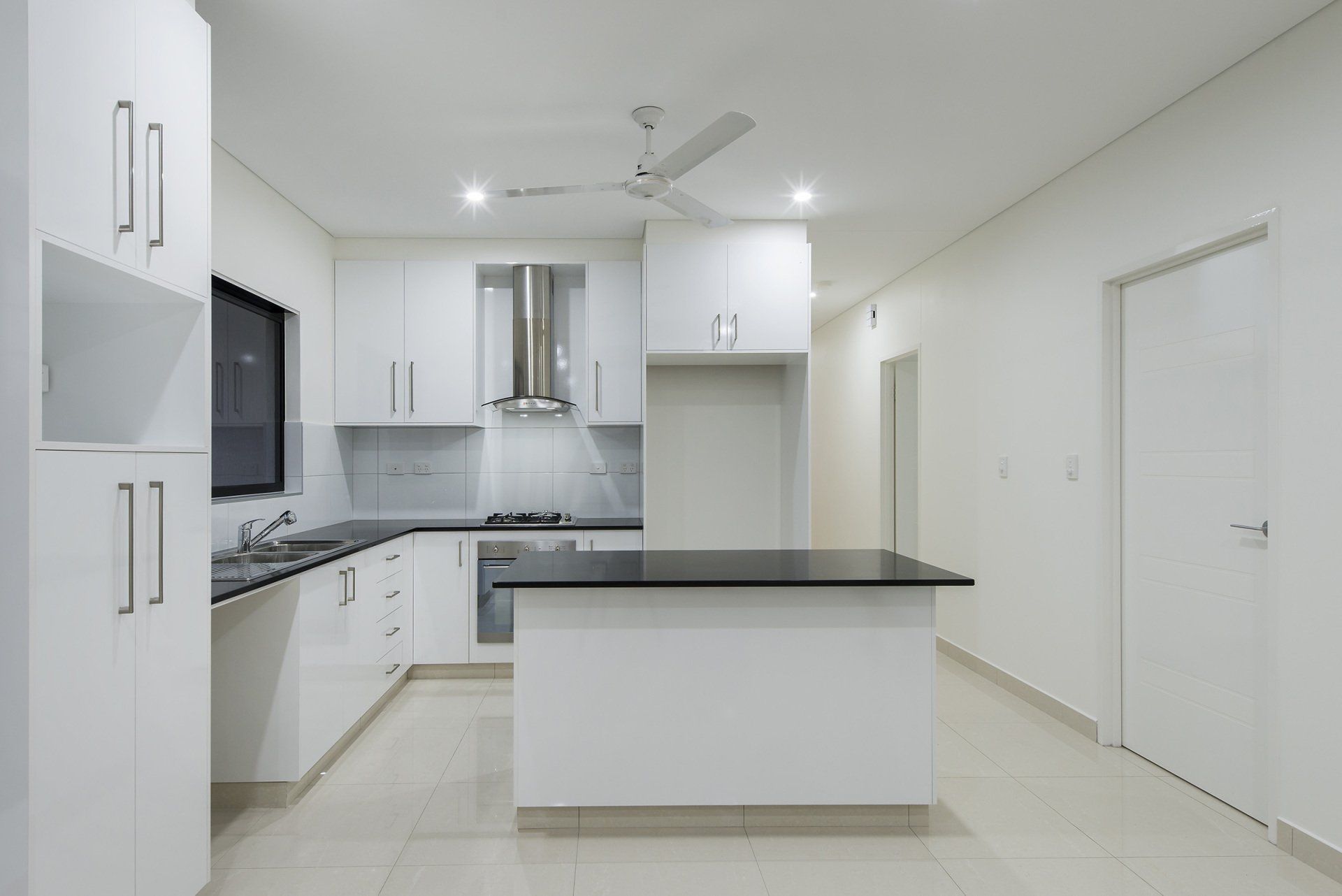 An empty kitchen with white cabinets and a black counter top