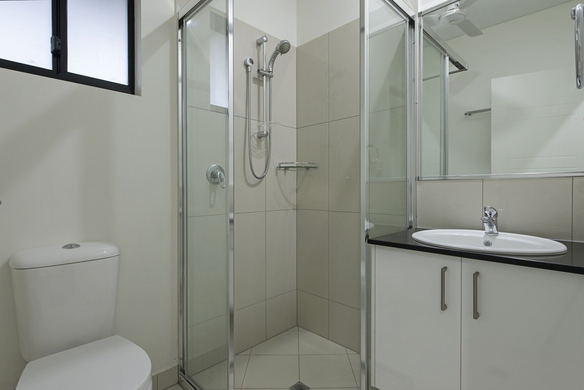 A bathroom with a toilet , sink and shower.