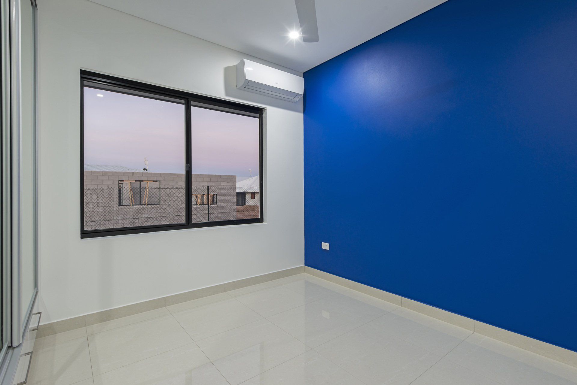 An empty room with a blue wall and a window.