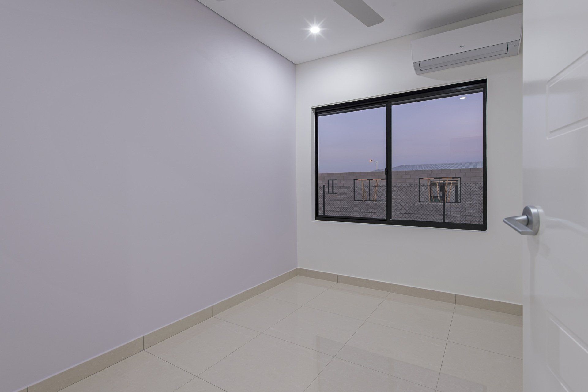 An empty room with two windows and a door.