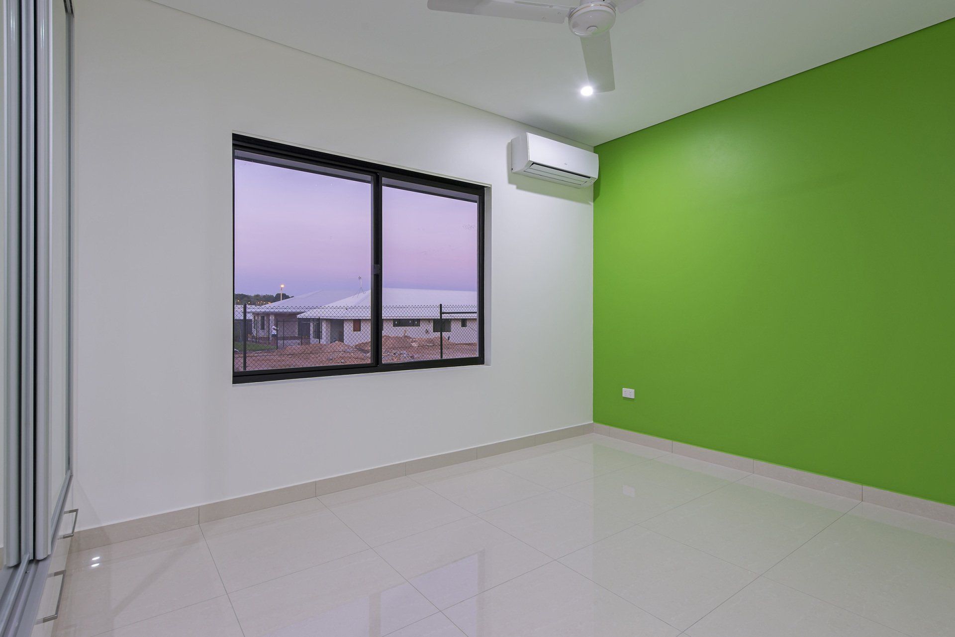 An empty room with a green wall and a window.