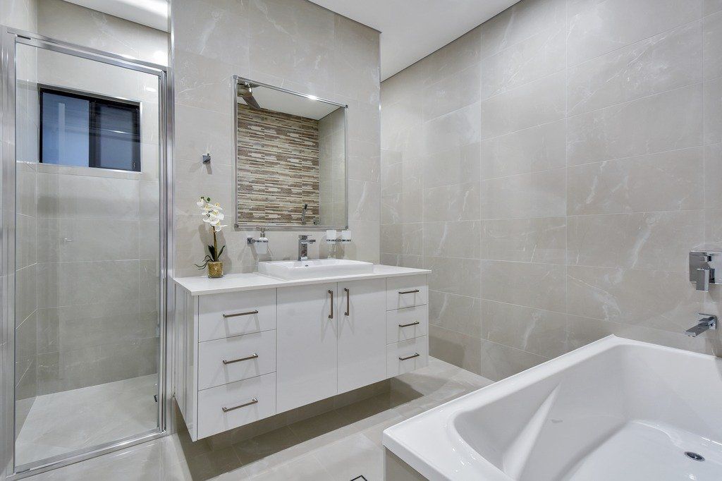 A bathroom with two sinks , a tub , a shower and a mirror.