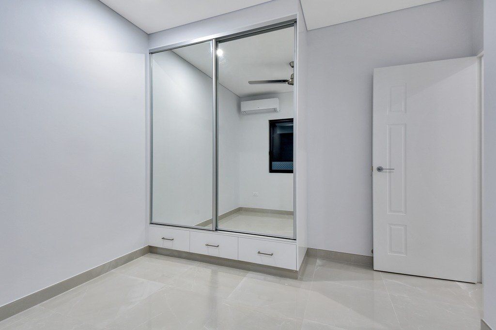 An empty bedroom with a large mirrored wardrobe and a door.