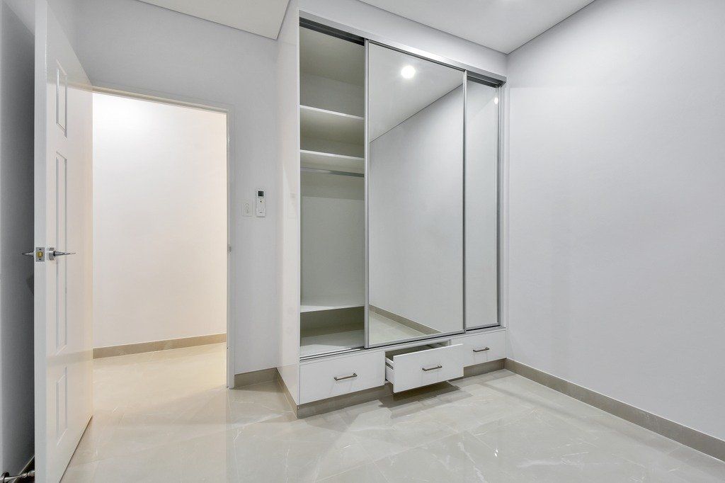 An empty bedroom with a large wardrobe and mirrors.