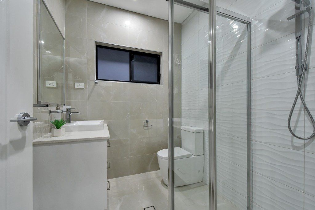 A bathroom with a toilet , sink , mirror and shower stall.