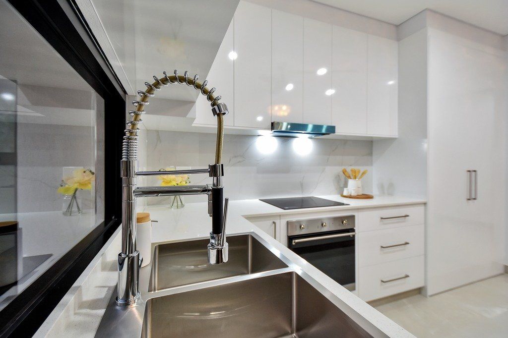 A kitchen with white cabinets and a stainless steel sink