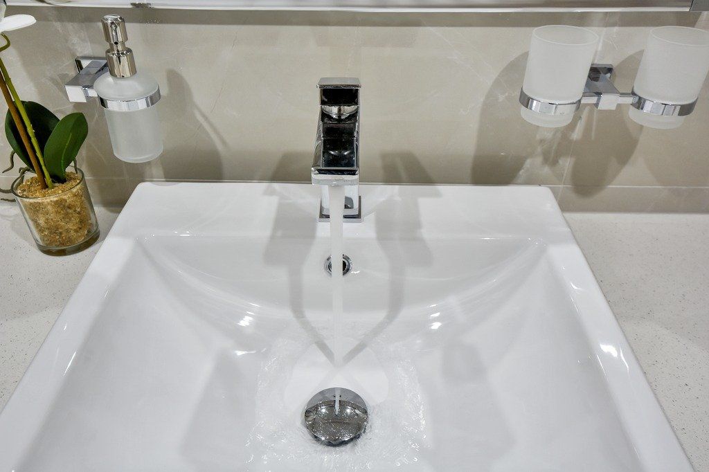 A bathroom sink with a faucet and a vase of flowers on the counter.