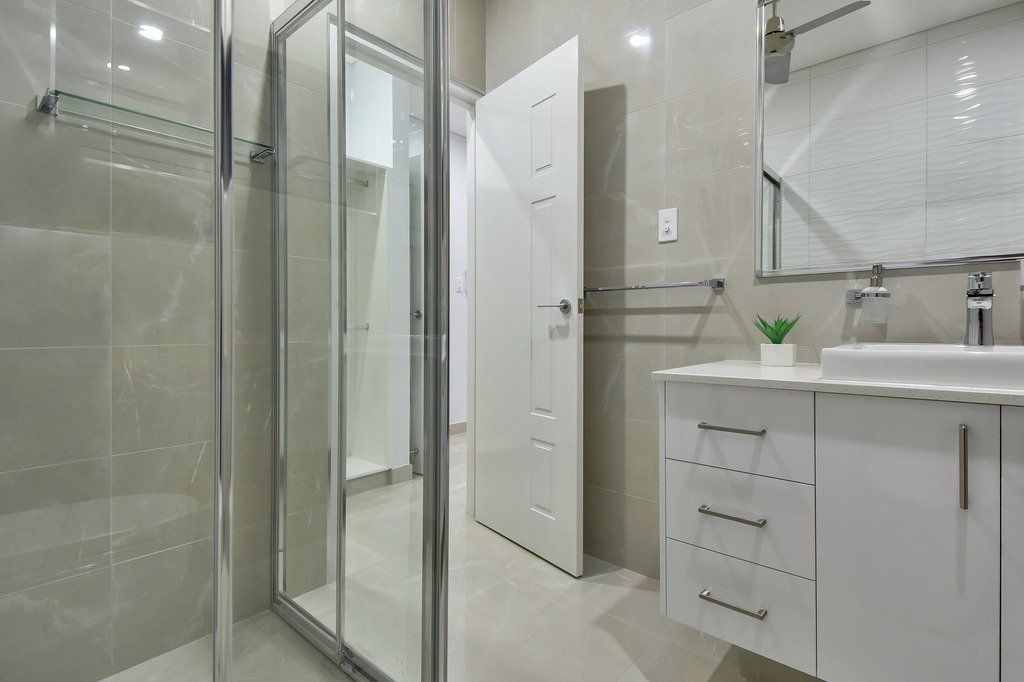 A bathroom with a walk in shower , sink and mirror.
