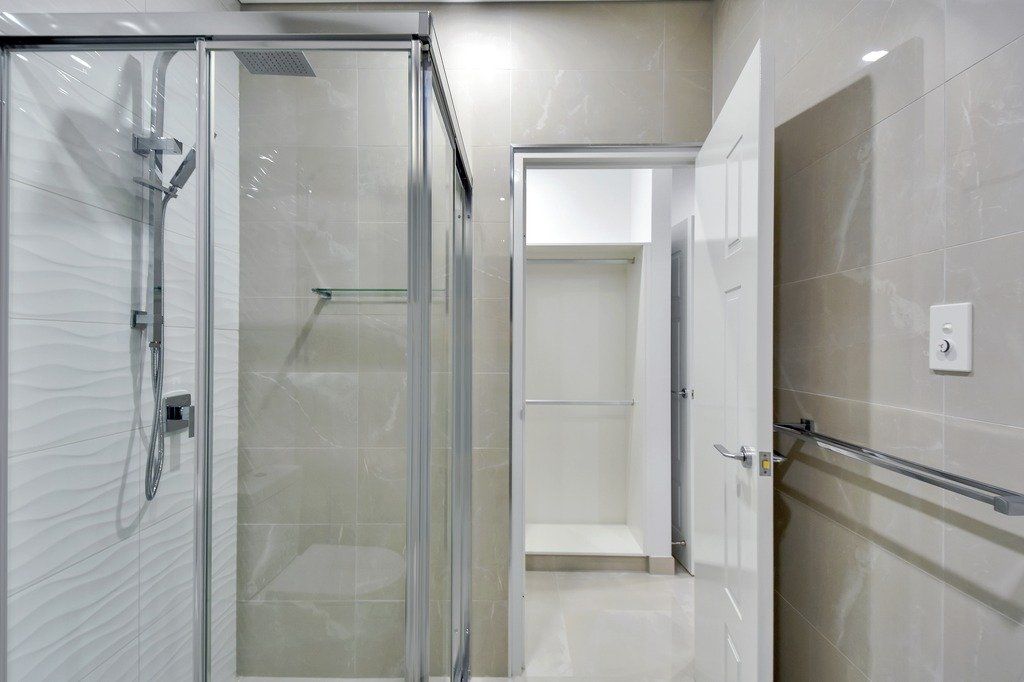 A bathroom with a walk in closet and a shower stall.