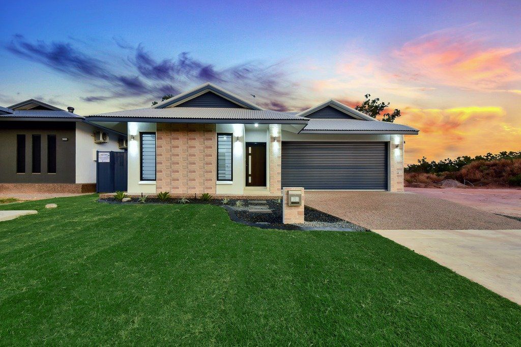 A large house with a lot of grass in front of it and a sunset in the background.