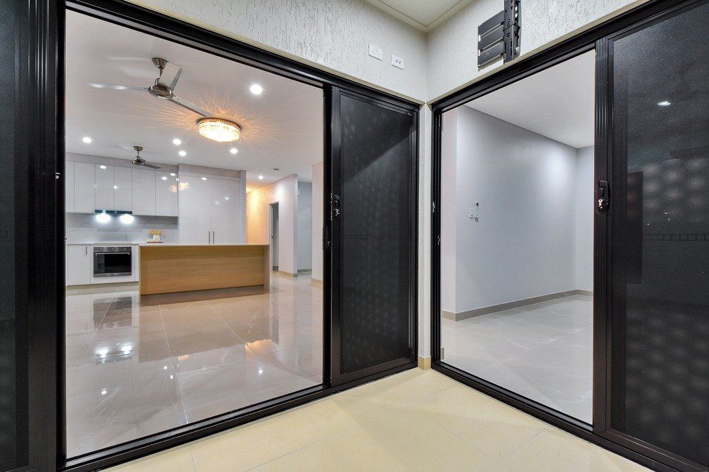 A room with a lot of windows and a kitchen in the background.