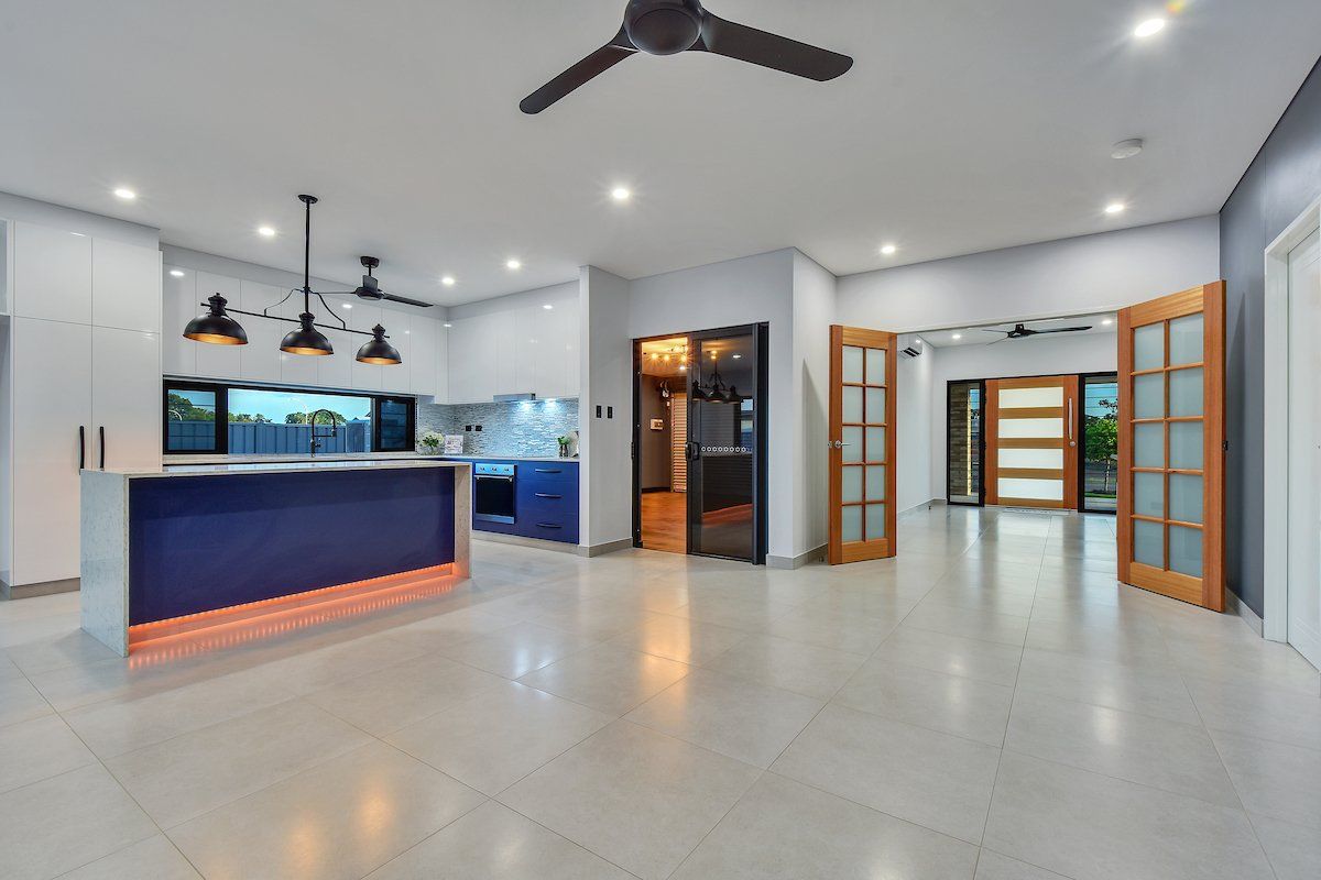 A large empty room with a kitchen and a ceiling fan