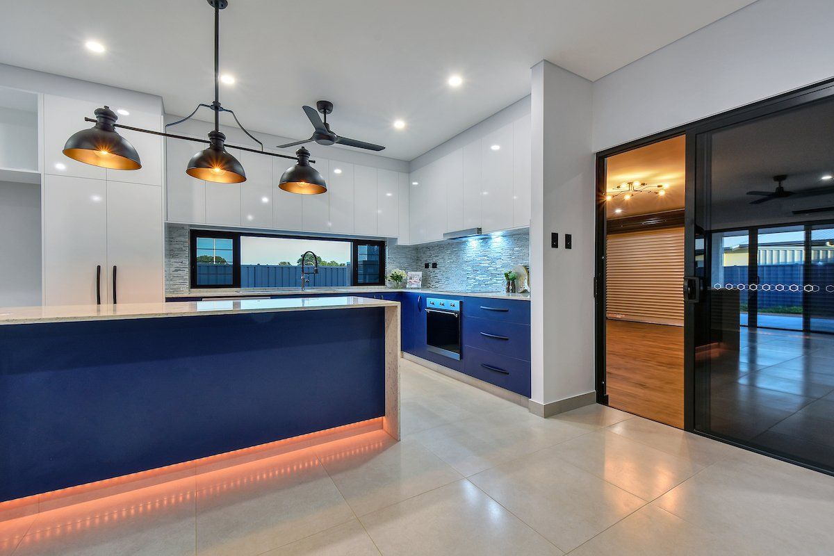 A kitchen with blue cabinets and white cabinets and a sliding glass door.