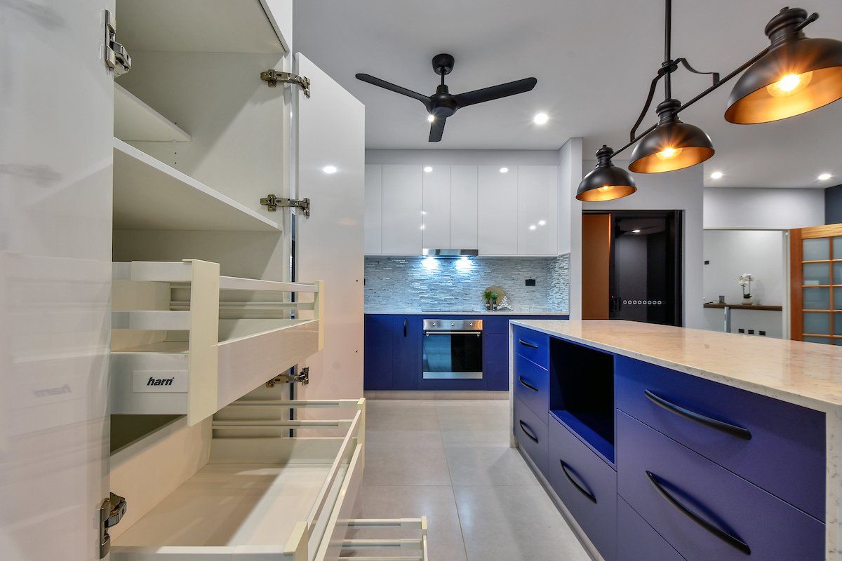 A kitchen with blue cabinets and white cabinets and a ceiling fan