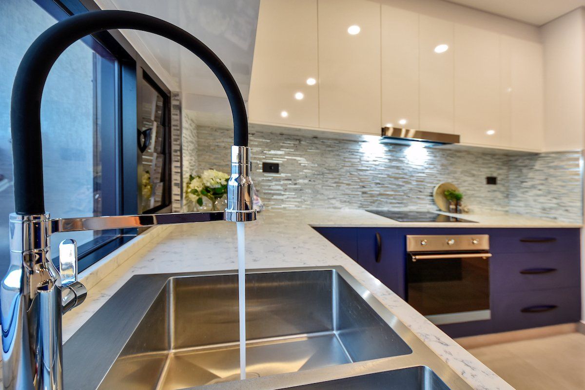A kitchen with a stainless steel sink and a black faucet