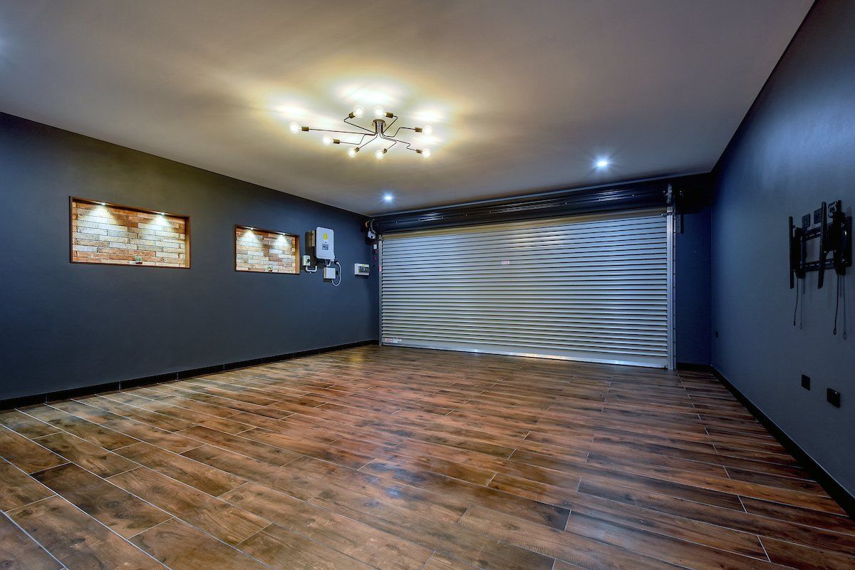 A large empty room with a wooden floor and a garage door.